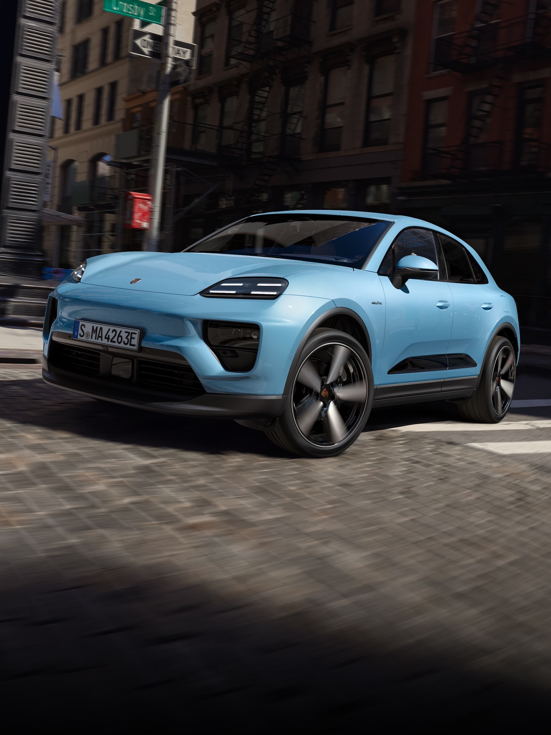 Una Porsche Macan completamente elettrica che guida lungo una strada in uno scenario urbano.