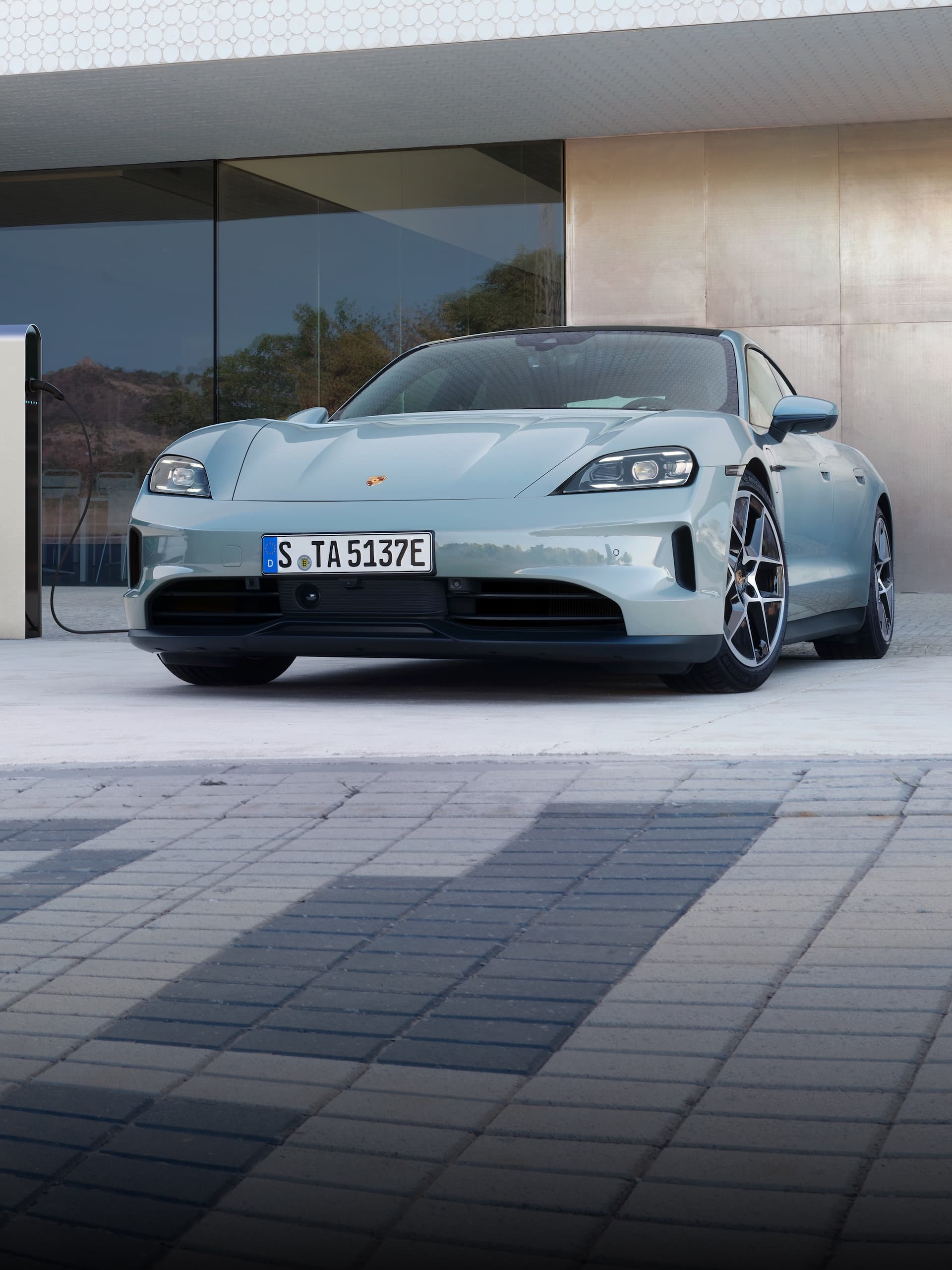 Una Porsche Taycan parcheggiata fuori davanti a un edificio moderno.